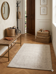 2' x 3' Rectangular Ivory & Beige Distressed Abstract Modern Washable Area Rug styled in a welcoming entryway beside a wooden bench.