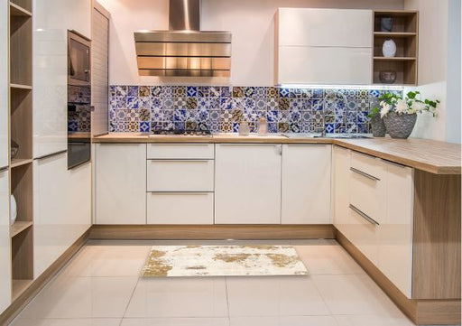 2' x 3' ivory and gold distressed abstract accent rug placed in a modern kitchen with light cabinetry and decorative tile backsplash.