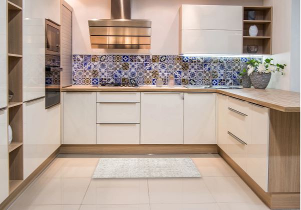 2' x 3' pale silver gray Persian-style accent rug placed in a modern kitchen with light cabinetry and decorative patterned backsplash.