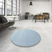 3 ft round denim blue contemporary rug placed in a modern loft-style living space with concrete flooring, large windows, and industrial décor.