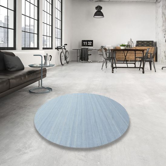 3 ft round denim blue contemporary rug placed in a modern loft-style living space with concrete flooring, large windows, and industrial décor.