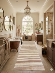 3' x 8' Runner Ivory & Blush Striped Modern Washable Area Rug placed in a luxurious bathroom with a freestanding tub, warm wood vanities, and spa-inspired transitional styling.