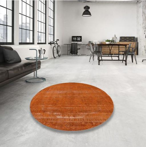 4' Round Orange Rust Mid-Century Modern Oriental Area Rug placed in an industrial loft living room with concrete floors and large windows.