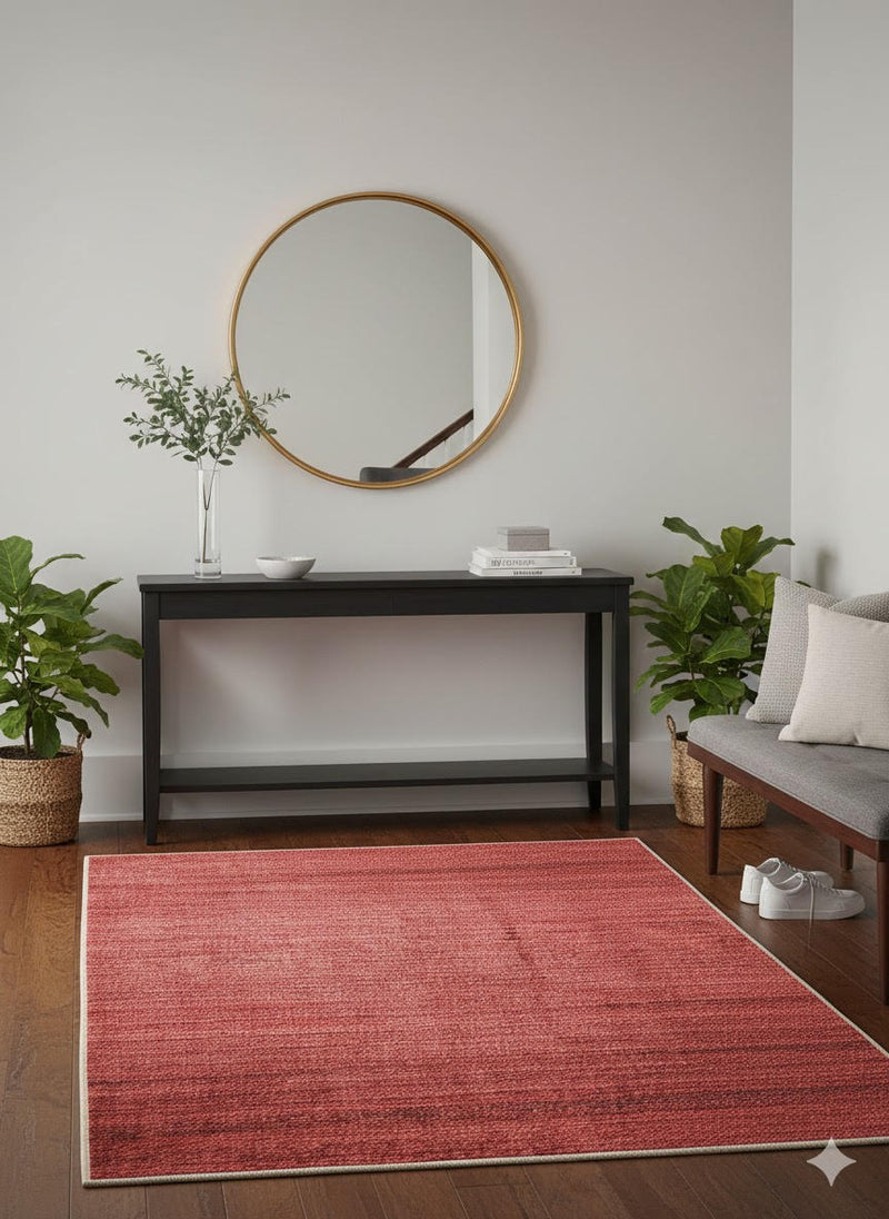 4' x 6' Rectangular Dusty Rose & Light Beige Solid Textured Modern Area Rug placed in a bright entryway with a black console table, round gold mirror, potted greenery, and dark wood floors.