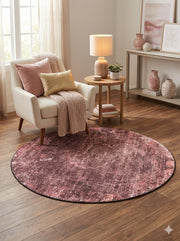 5' Round Deep Mauve Pink & Blush Distressed Abstract Modern Area Rug styled in a cozy living room beneath an accent chair and side table.