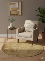 5' round soft golden ochre and warm honey washable solid textured area rug styled in a cozy reading nook with a neutral accent chair, gold side table, and warm minimalist décor.