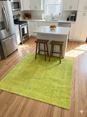 5' x 5' square lime green & solid modern area rug placed in a contemporary kitchen beside a wood island..