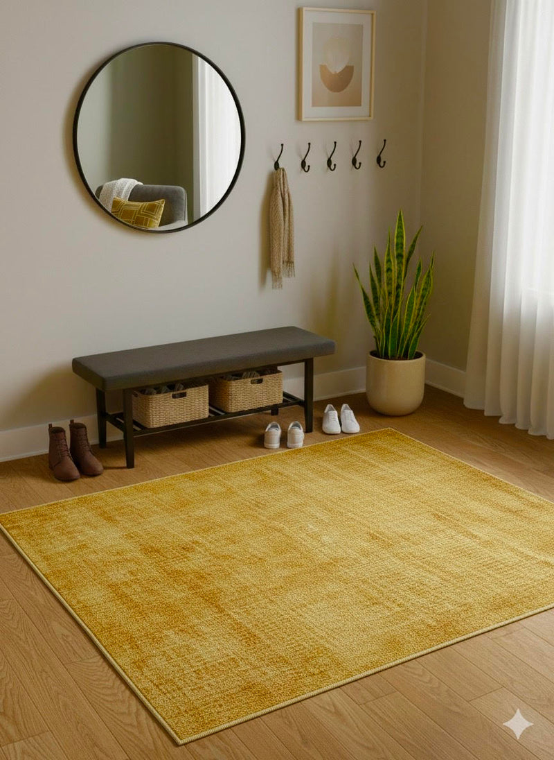 5' x 5' square mustard yellow & warm gold solid modern area rug styled in a bright entryway with a wooden bench, round wall mirror, coat hooks, and potted greenery.