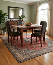 5' x 6' Rectangular Rust Red & Navy Blue Distressed Floral Medallion Traditional Area Rug styled in a dining room with a wooden dining table and dark upholstered chairs.