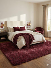 5' x 7.7' deep burgundy wine red undertones solid plush area rug styled in a bedroom with neutral bedding and burgundy decor.