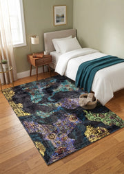 5' x 7' Rectangular Black Multicolor Distressed Floral Abstract Vintage Area Rug placed in a bedroom beside a single upholstered bed with white bedding.