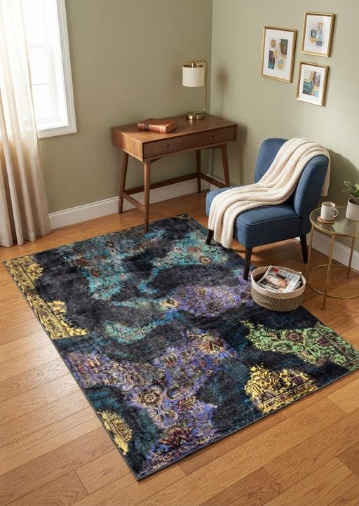 L5' x 7' Rectangular Black Multicolor Distressed Floral Abstract Vintage Area Rug styled in a cozy seating area with a blue accent chair and wooden desk.