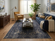 5' x 7' Rectangular Charcoal Black & Gold Distressed Floral Medallion Vintage Washable Area Rug styled in a living room with a navy blue sofa and wooden coffee table.