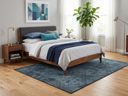 5' x 7' Rectangular Dark Blue & Gray Distressed Geometric Abstract Modern Area Rug styled in a bedroom with a wooden bed and navy blue bedding.