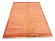 5' x 7' Rectangular Peach Coral & Rust Solid Textured Border Modern Area Rug featuring a softly distressed peach center, rust geometric border, and subtle gold accents.