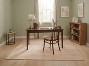 5' x 7' Rectangular Peach & Ivory Distressed Solid Minimalist Modern Washable Area Rug styled in a home office with a wooden desk and brown chair.