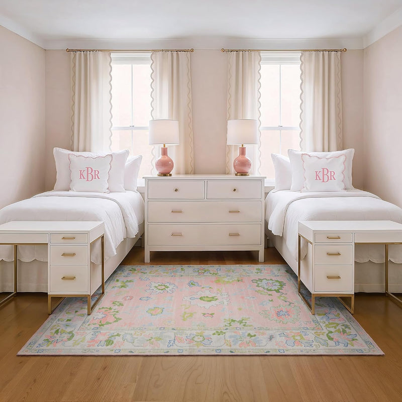 5' x 7' Rectangular Pink Multicolor Floral Traditional Washable Area Rug placed in a charming girls’ bedroom between two twin beds with pink monogram pillows and white furniture.