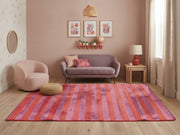 5' x 7' Rectangular Pink & Orange Purple Striped Abstract Modern Area Rug styled in a living room with a lavender sofa and blush accent chair.