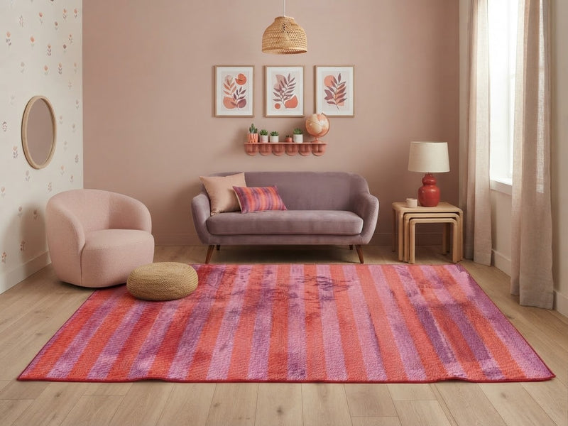 5' x 7' Rectangular Pink & Orange Purple Striped Abstract Modern Area Rug styled in a living room with a lavender sofa and blush accent chair.