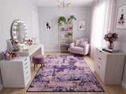5' x 7' Rectangular Purple & Lavender Pink Distressed Abstract Modern Area Rug styled in a vanity room with a white makeup desk and lavender armchair.
