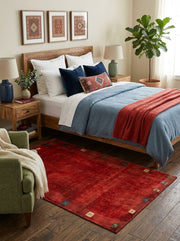 5' x 7' Rectangular Red Multicolor Distressed Solid Tribal Traditional Area Rug placed in a bedroom with a wooden bed and blue bedding.