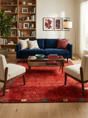 5' x 7' Rectangular Red Multicolor Distressed Solid Tribal Traditional Area Rug styled in a living room with a navy blue sofa and wooden coffee table.