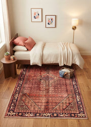 5' x 7' Rectangular Rust Red Burgundy Distressed Medallion Traditional Vintage Area Rug placed in a bedroom with a wooden bed and white bedding.