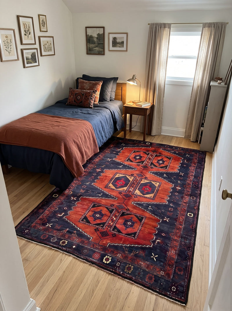5' x 7' Rectangular Rust Red & Navy Blue Tribal Geometric Medallion Traditional Area Rug placed in a bedroom beside a wooden bed with navy bedding and rust throw blanket.