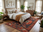 5' x 7' Rectangular Rust Red & Navy Blue Tribal Geometric Southwestern Washable Area Rug placed in a bedroom with a white bed and wooden nightstands.