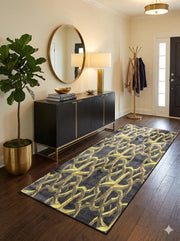 5' x 7' black and gold interlocking geometric rectangular area rug placed in an entryway with a black console table and brass decor.
