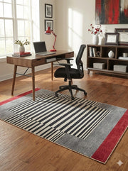 5' x 7' black, ivory, and red modern striped rectangular area rug styled in a home office with a wooden desk, black task chair, and sunlit wood floors.