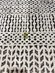5' x 7' ivory and black charcoal geometric textured rectangular area rug close-up showing woven texture and contrasting geometric motifs.