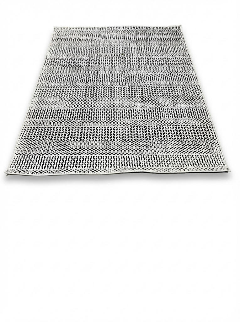 5' x 7' ivory and black charcoal geometric textured rectangular area rug featuring layered linear and dotted patterns on a white background.
