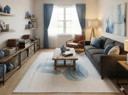 5' x 7' ivory and dusty blue abstract modern rectangular area rug styled in a bright living room with a gray sofa and wood flooring.