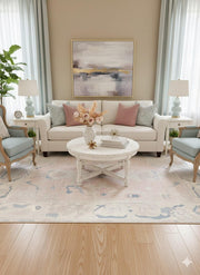 5' x 7' ivory cream and blush pink washable abstract vintage area rug styled in a bright living room with a neutral sofa, pastel accent pillows, and soft blue armchairs.
