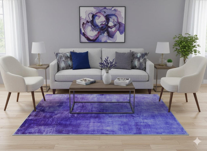5' x 7' purple soft blue & gray tonal modern abstract rectangular area rug styled in a bright contemporary living room with a light gray sofa, accent chairs, abstract wall art, and light wood flooring.