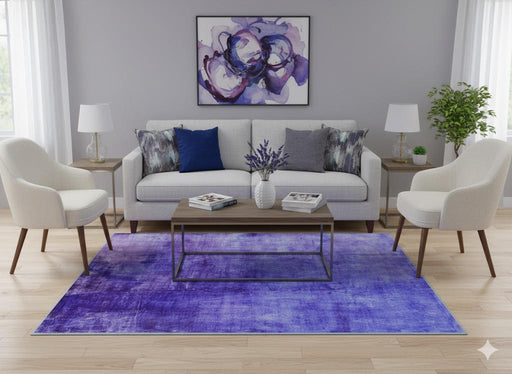 5' x 7' purple soft blue & gray tonal modern abstract rectangular area rug styled in a bright contemporary living room with a light gray sofa, accent chairs, abstract wall art, and light wood flooring.