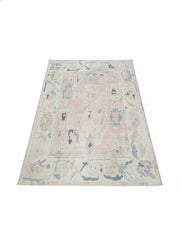 5' x 7' washable area rug featuring an ivory and cream base with blush pink and soft blue abstract vintage motifs in a lightly distressed pattern.