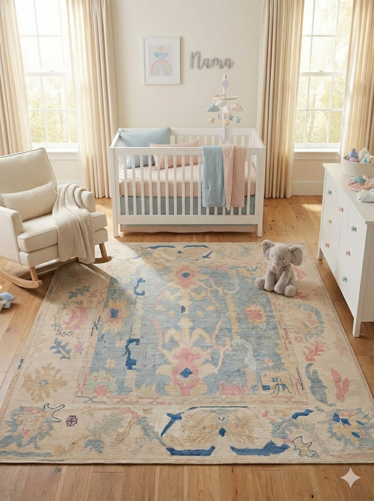 5' x 8' Light Blue Multi Color Pastel Distressed Area Rug placed in a soft neutral nursery with a white crib, white rocking chair, light wood floors, and sheer window curtains.