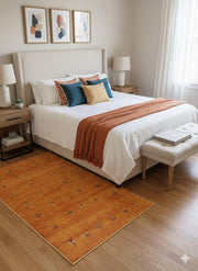 5' x 8' Rectangle Gold Rust Brown Ivory Tribal Minimalist Area Rug placed in a bright bedroom with neutral bedding, layered accent pillows, and soft natural light.