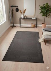 5' x 8' Rectangular Black Charcoal & Deep Graphite Solid Textured Washable Area Rug placed in a modern entryway with light wood floors.