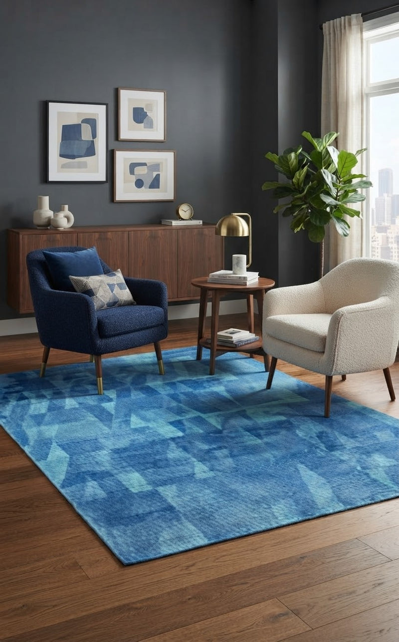 5' x 8' Rectangular Blue & Light Blue Abstract Geometric Modern Area Rug styled in a living room with a navy blue accent chair and cream upholstered chair.