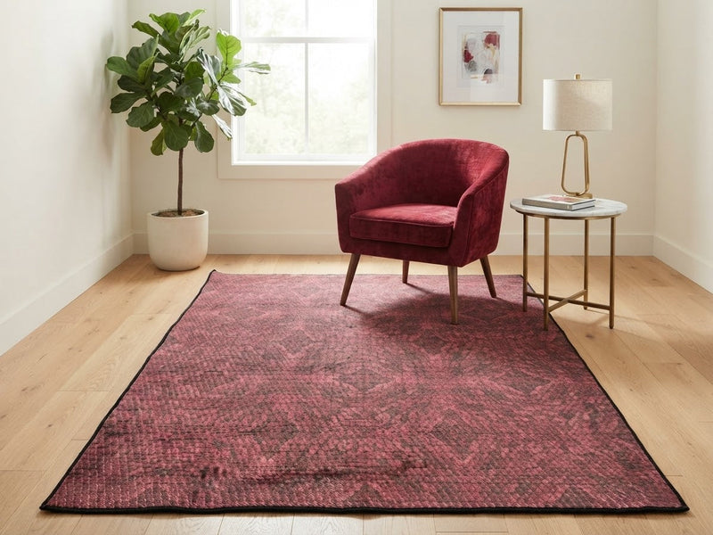 5' x 8' Rectangular Burgundy Red & Black Distressed Geometric Modern Area Rug styled in a living room with a burgundy accent chair and round side table.
