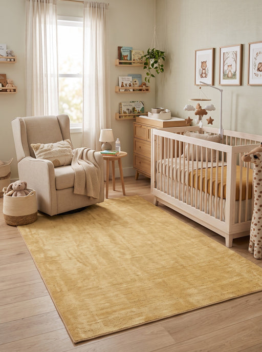 5' x 8' Rectangular Light Yellow & Cream Distressed Solid Modern Area Rug placed in a nursery with a white crib and beige rocking chair.
