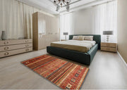 5' x 8' Rectangular Red Multi Color Contemporary Oriental Area Rug placed in a bedroom setting beside a modern platform bed.