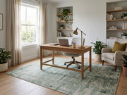 5' x 8' Rectangular Sage Green & Ivory Distressed Floral Ornamental Border Vintage Transitional Area Rug placed beneath a wooden office desk with a white upholstered chair.