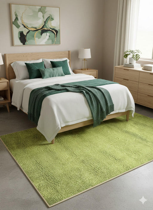 5' x 8' avocado green and cream washable solid plush area rug styled in a modern bedroom with a light wood bed frame, white bedding, and deep green accent pillows.
