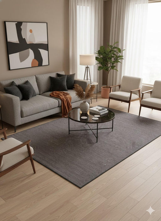 5' x 8' black charcoal deep graphite washable solid textured area rug styled in a modern living room with a gray sofa, glass coffee table, and warm neutral décor.