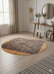 6 ft round brown and tan light wood tone solid border modern area rug placed in a bright entryway with a console table, bench seating, and neutral decor.