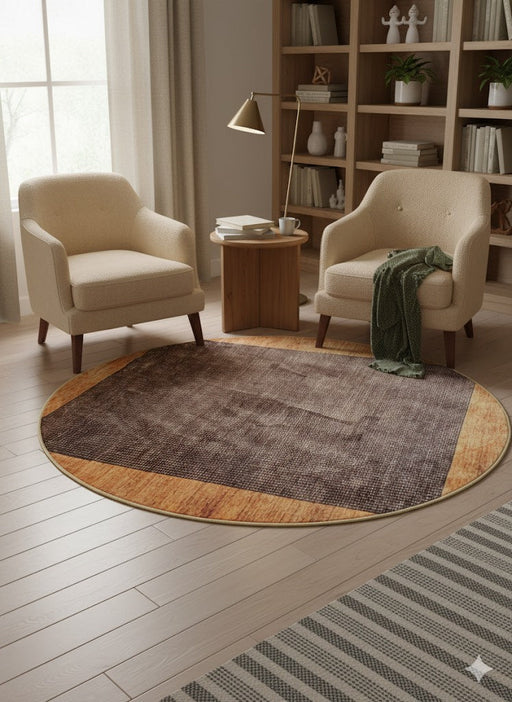 6 ft round brown and tan light wood tone solid border modern area rug styled in a cozy reading corner with two upholstered chairs and a small side table.